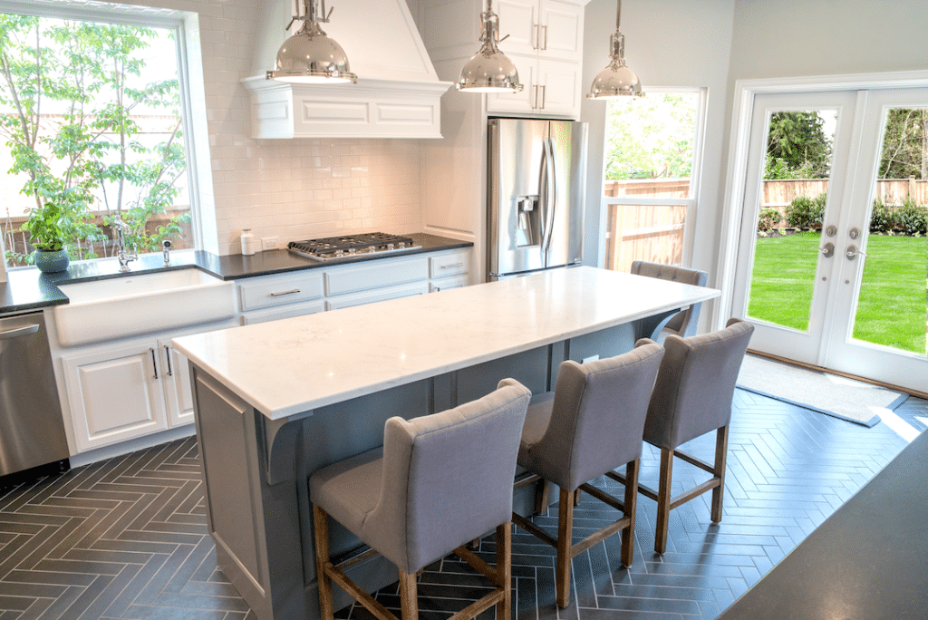 Custom white kitchen with gray island and herringbone floor.