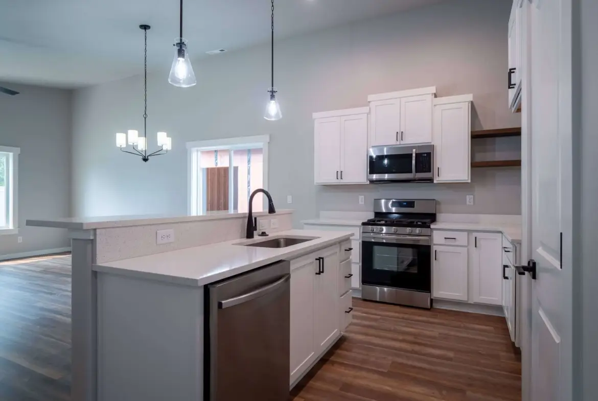 white modern kitchen with glass tiles and SS appliances