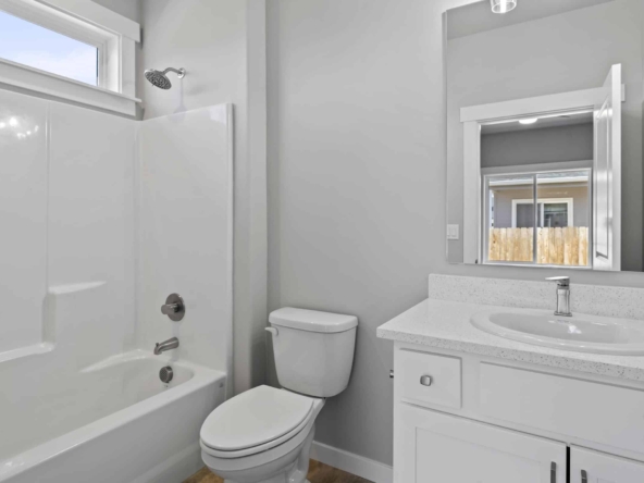 Minimalist bathroom with white countertop, sleek mirror, modern sink, and combined tub and shower.
