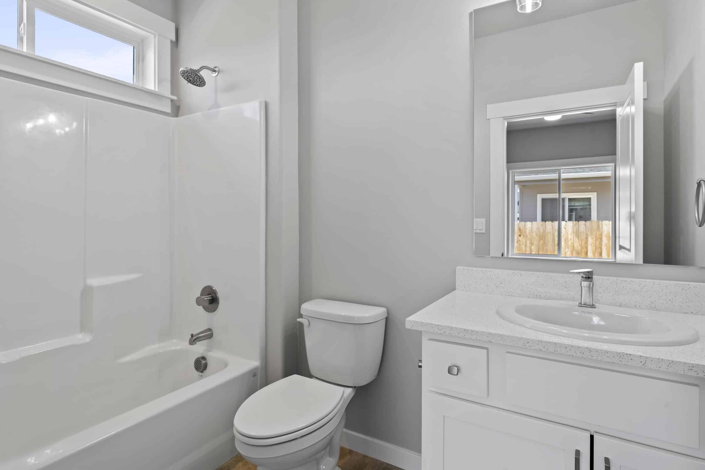 Minimalist bathroom with white countertop, sleek mirror, modern sink, and combined tub and shower.