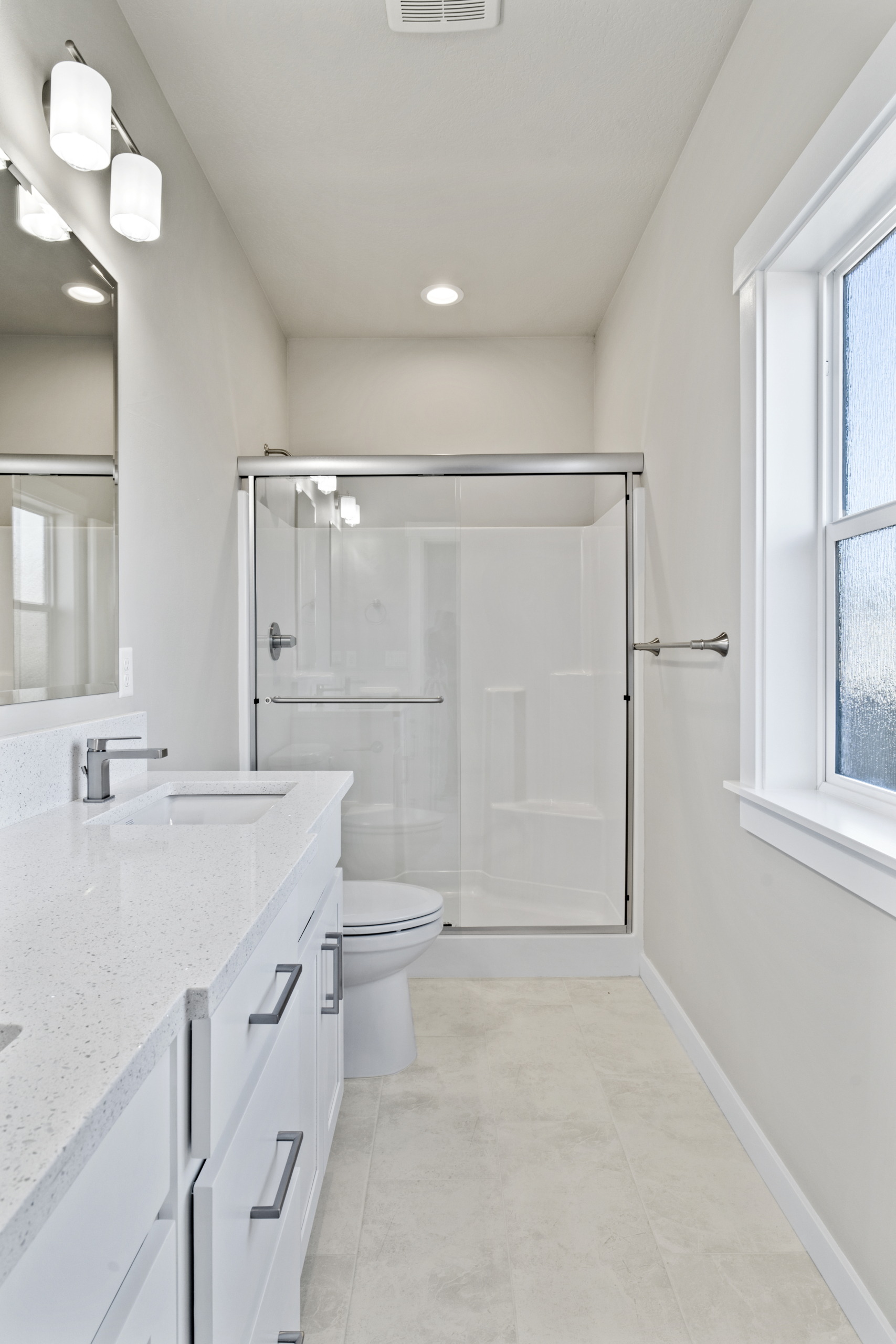 a master bathroom with a serene ambiance. the room features pristine white countertops, a sleek sink, and a stylish mirror that complements the overall aesthetic. A refreshing shower
