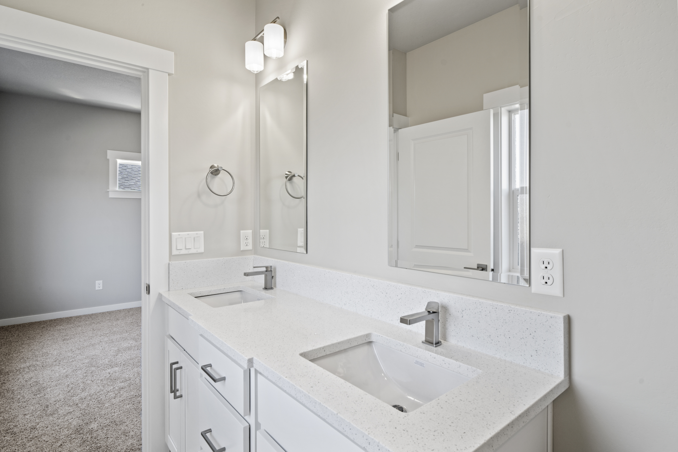 A spacious master bathroom featuring white countertops with two large mirrors, perfectly positioned above two stylish sinks.